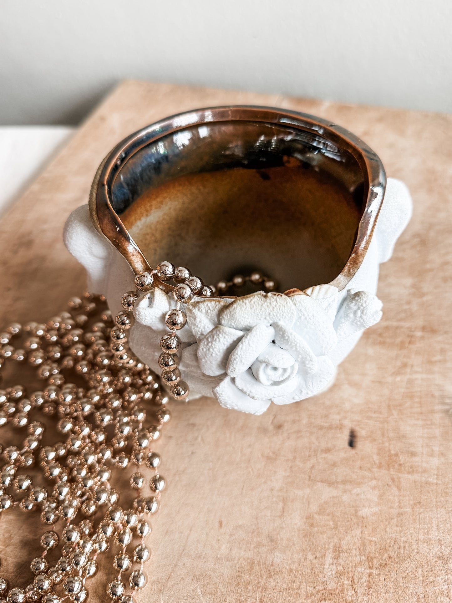 Inside of white indoor planter with brown glaze and rose motif.