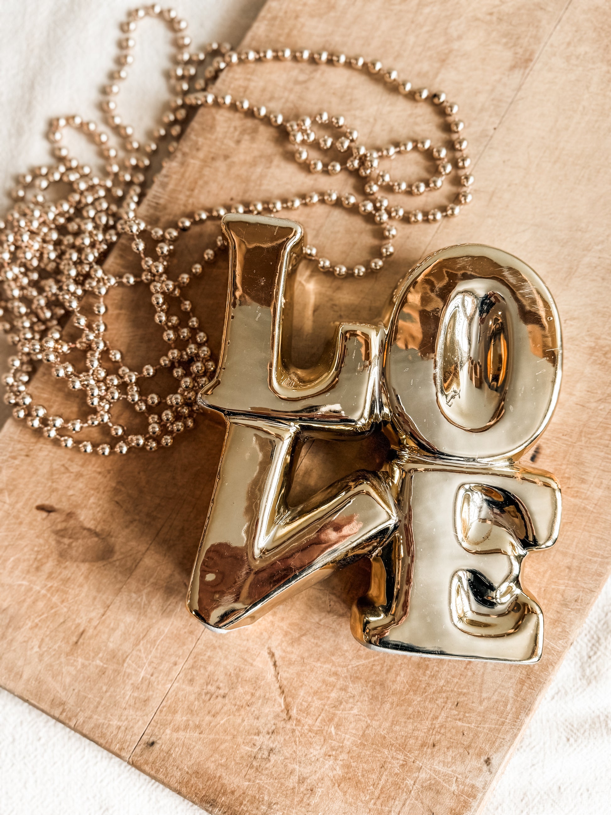 Decorative ceramic block letters spelling the word love in gold. 